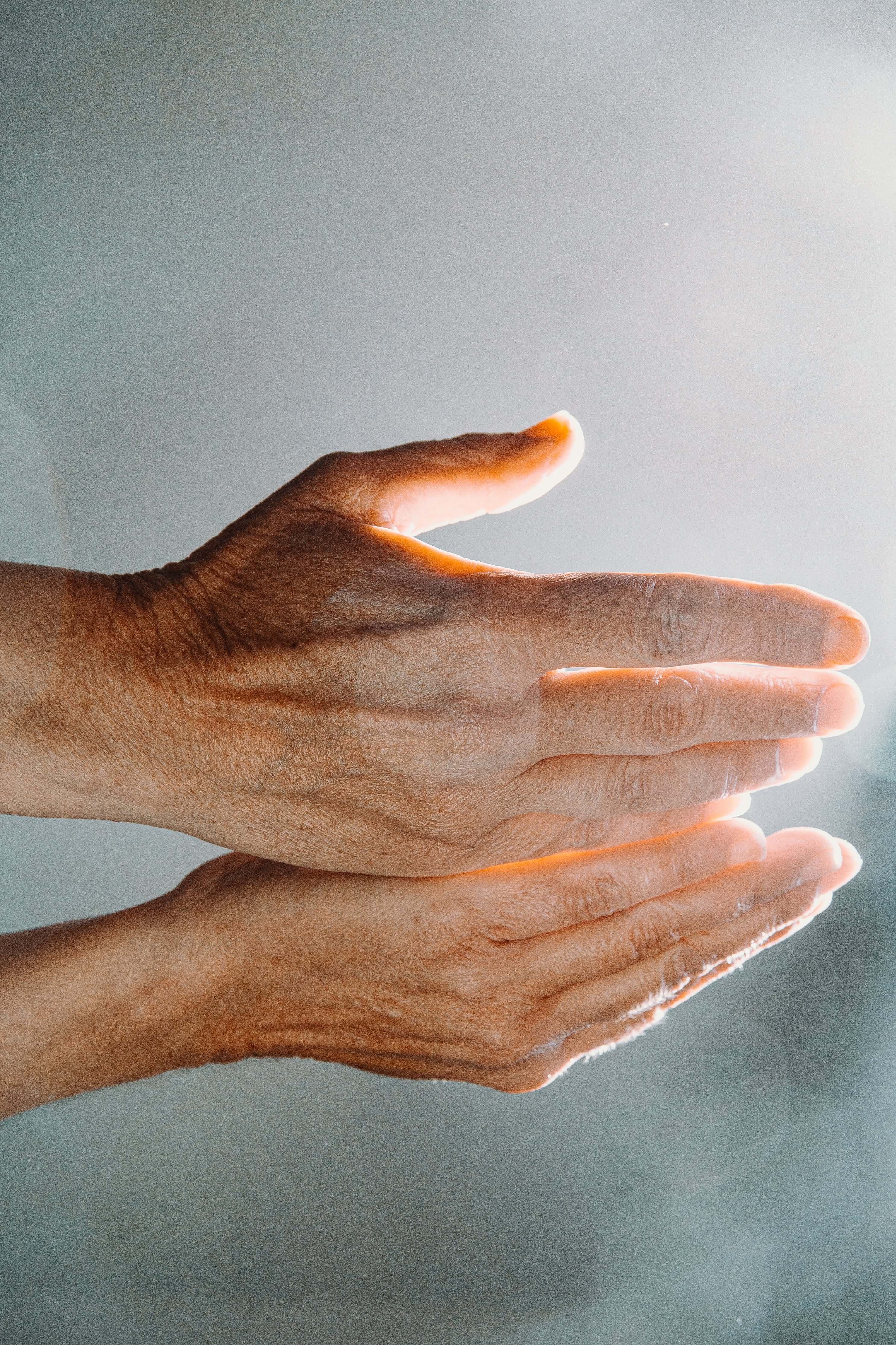 Two hands held together against a light gray background
