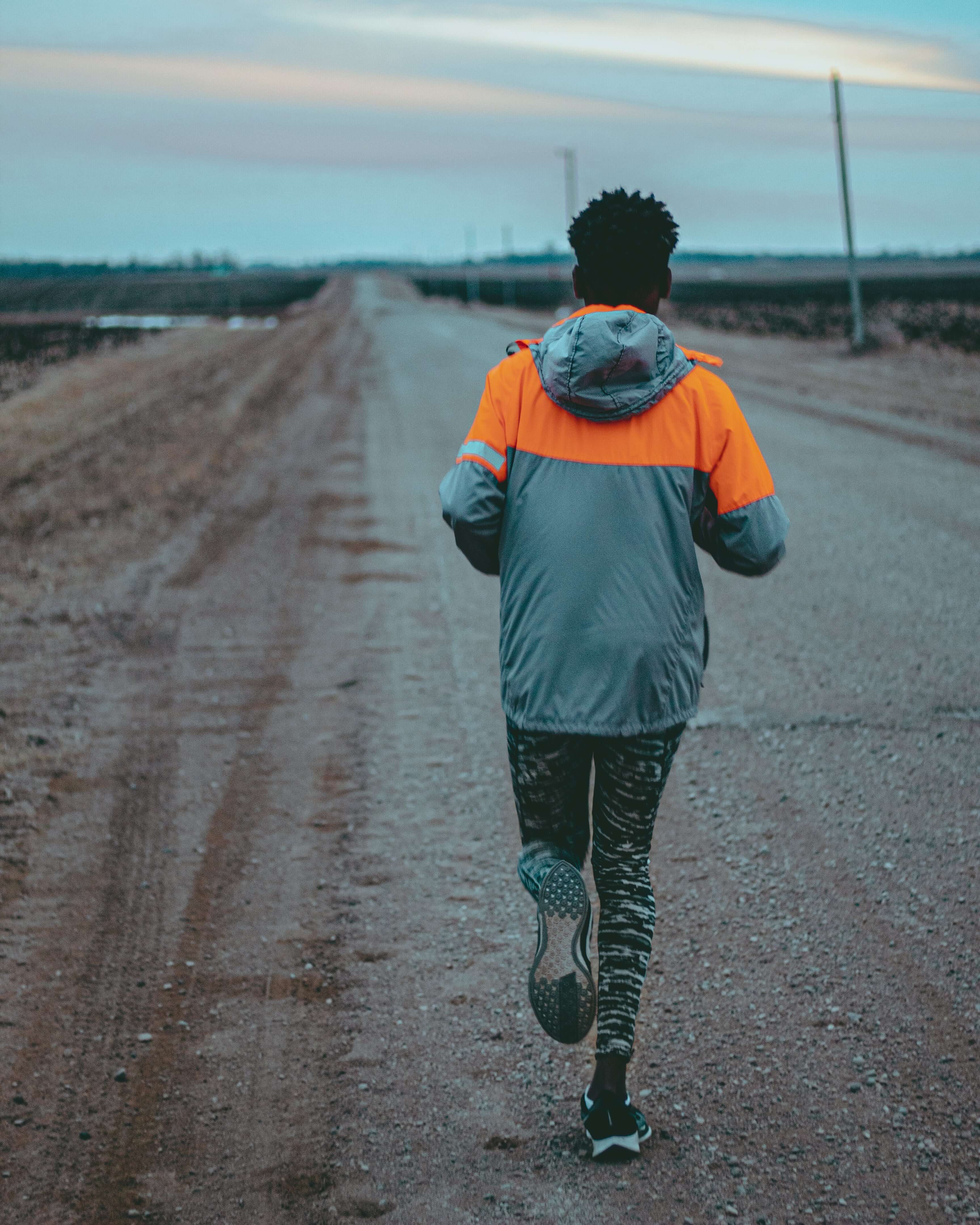 Person running on a road with a colorful jacket
