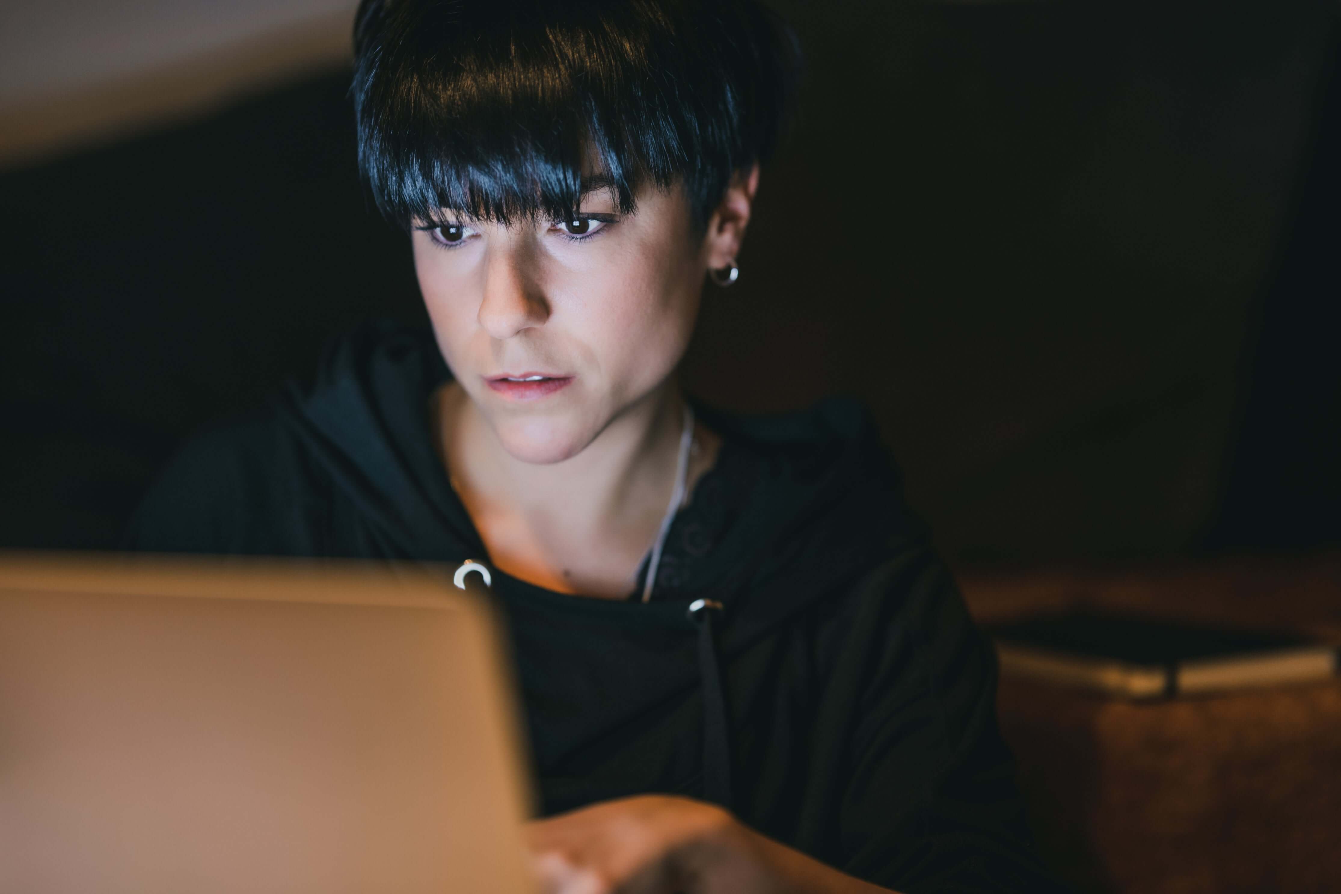 Person using a laptop in a dimly lit room
