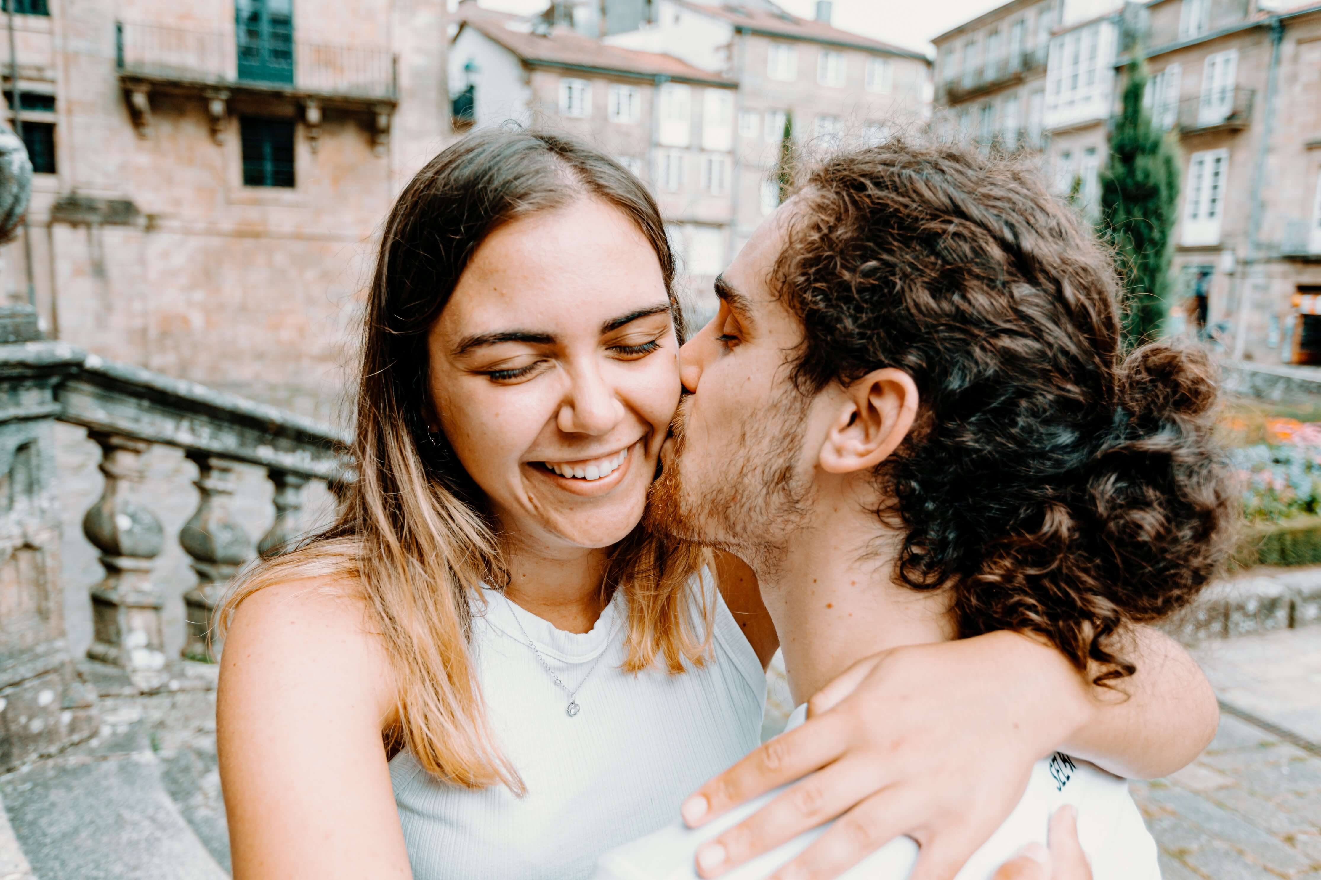 Man kissing a woman on the cheek in an urban setting

