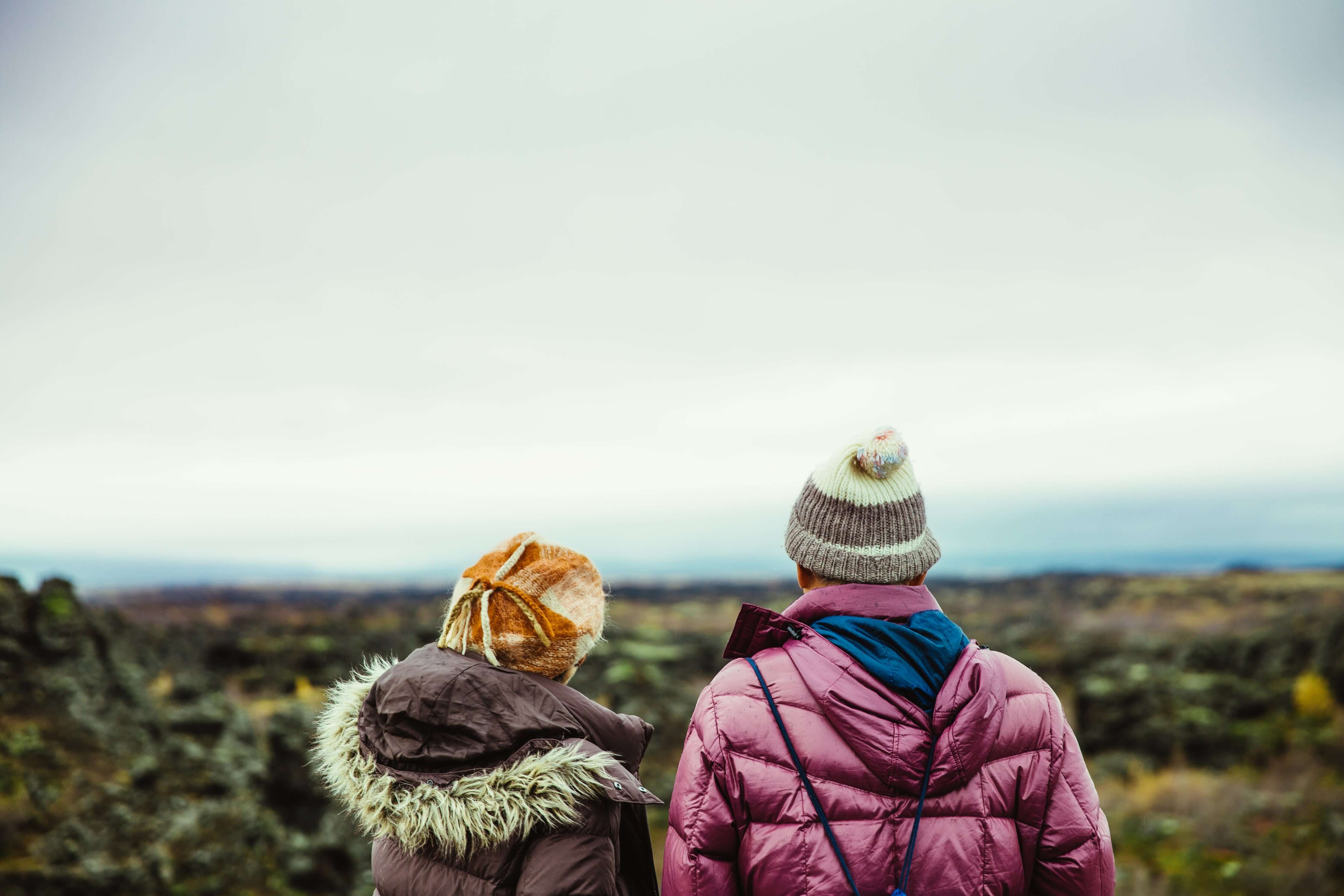 Two people in winter clothing looking out over a landscape
