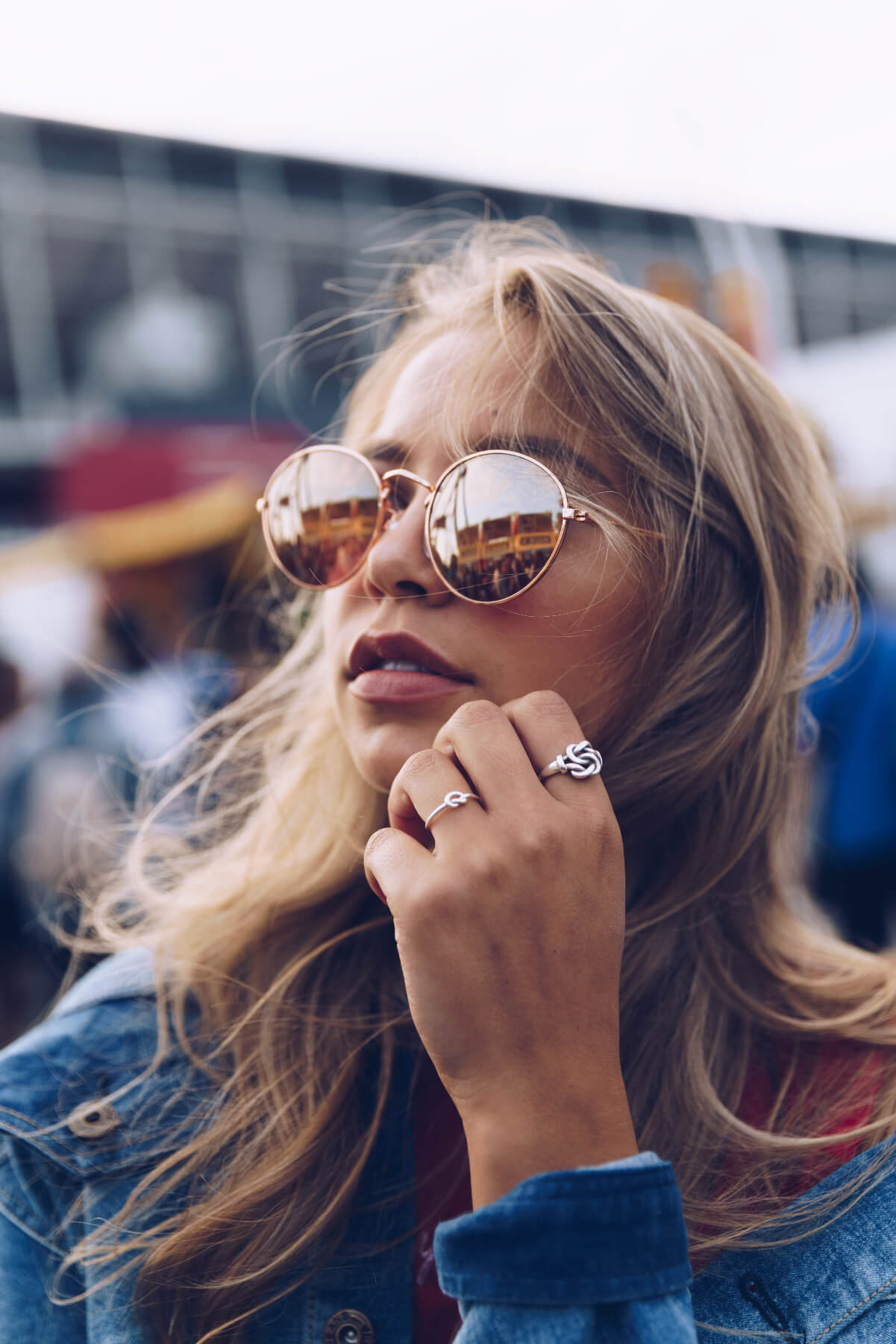Woman wearing reflective sunglasses and a ring, with a blurred background
