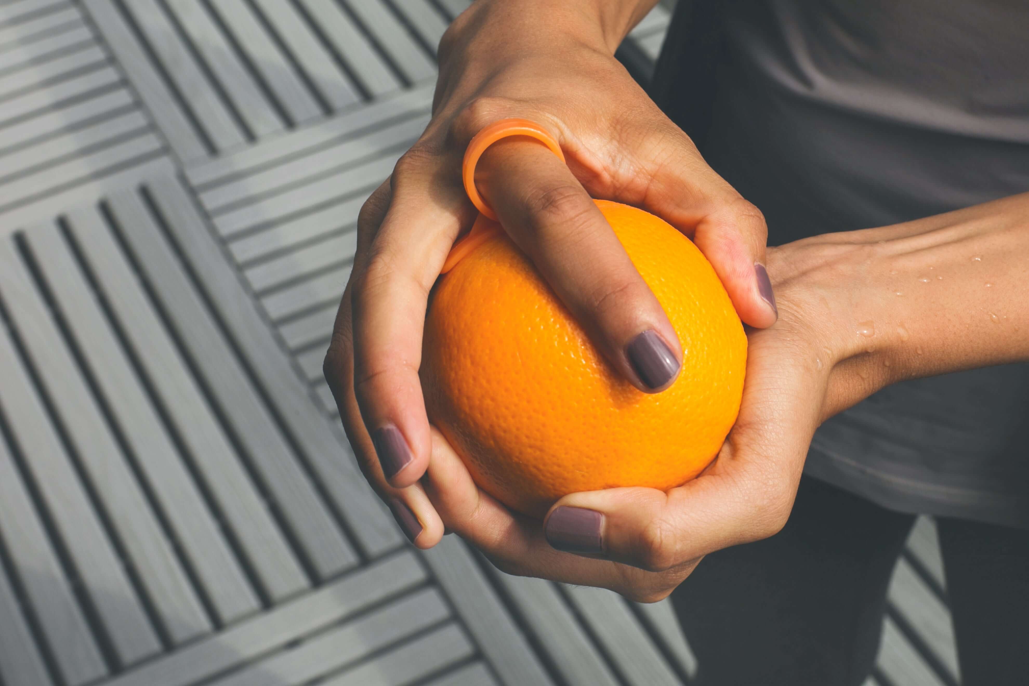 Person holding an orange on a textured surface
