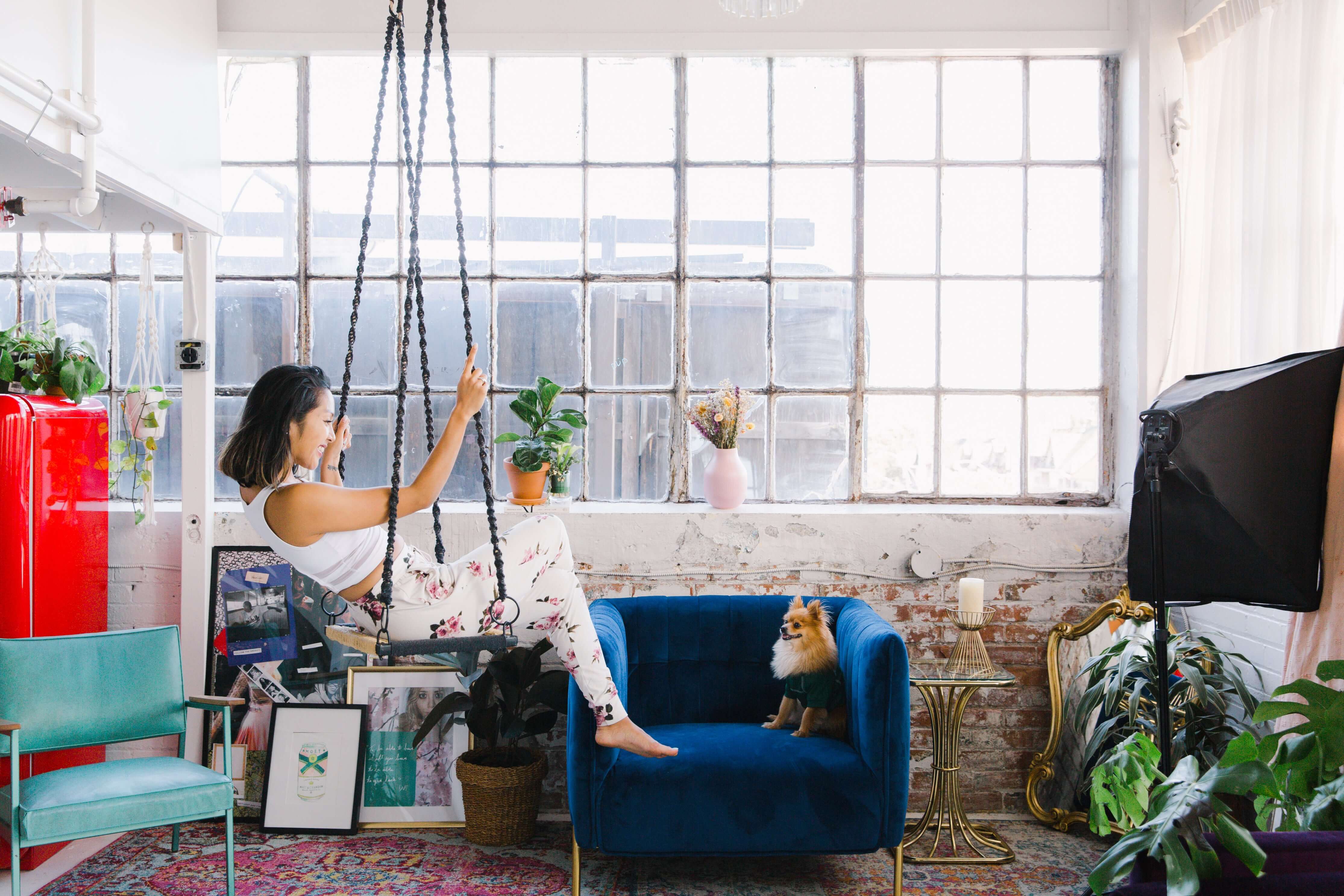 Woman interacting with a swing in a stylish living room with plants and decor.
