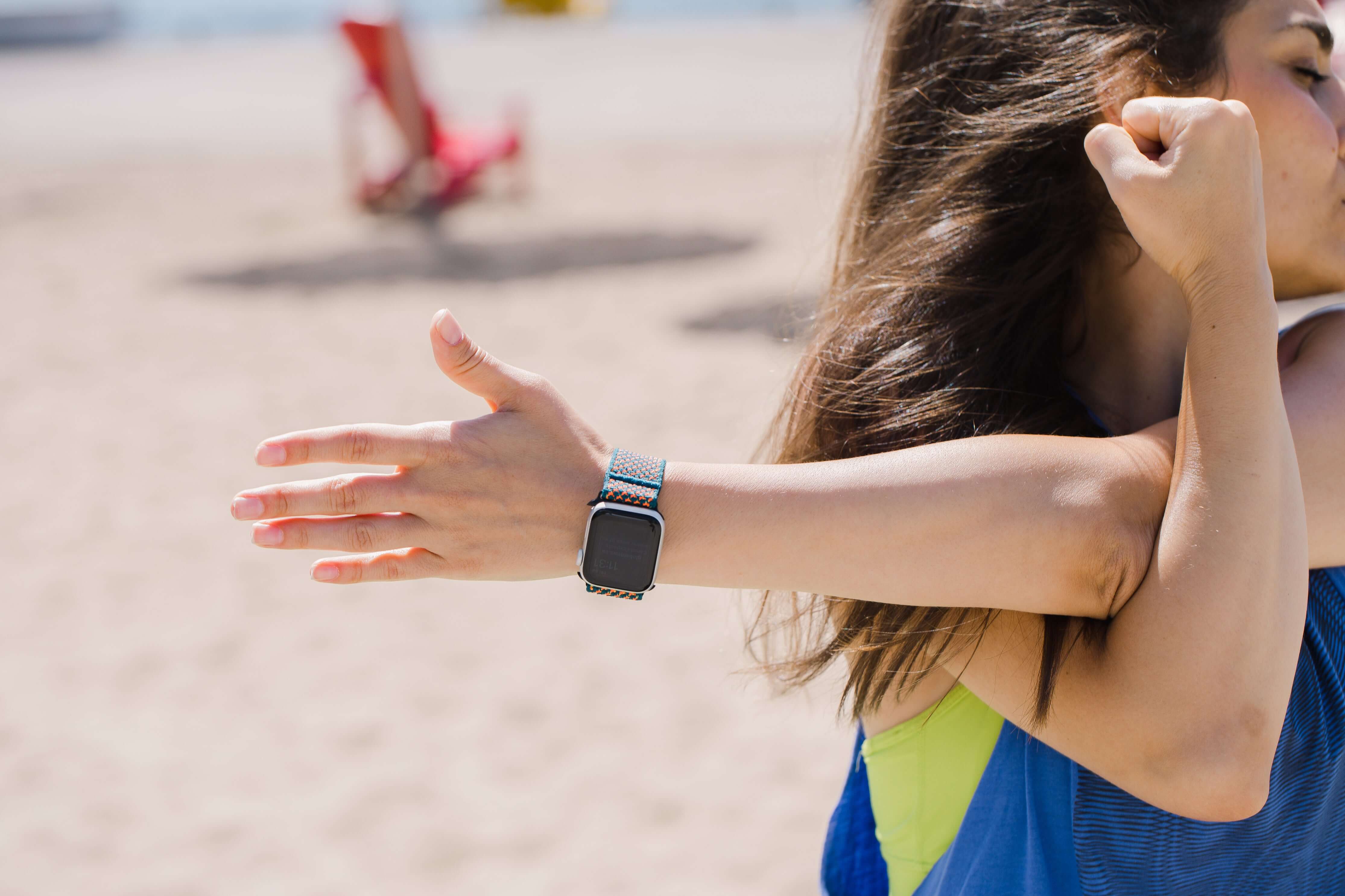 Woman stretching outdoors with a smartwatch on her wrist
