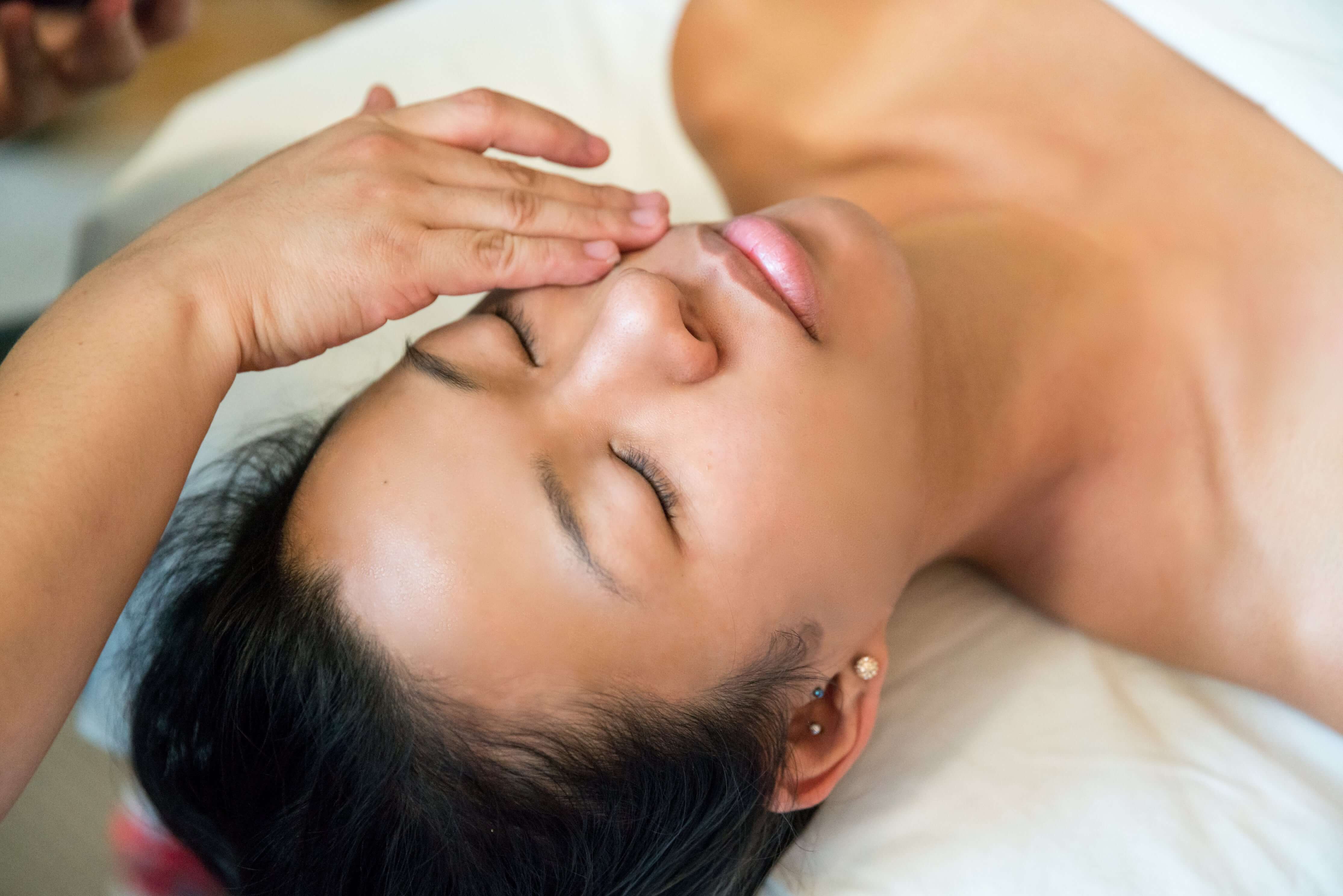 Woman receiving a facial massage with a close-up of her face.
