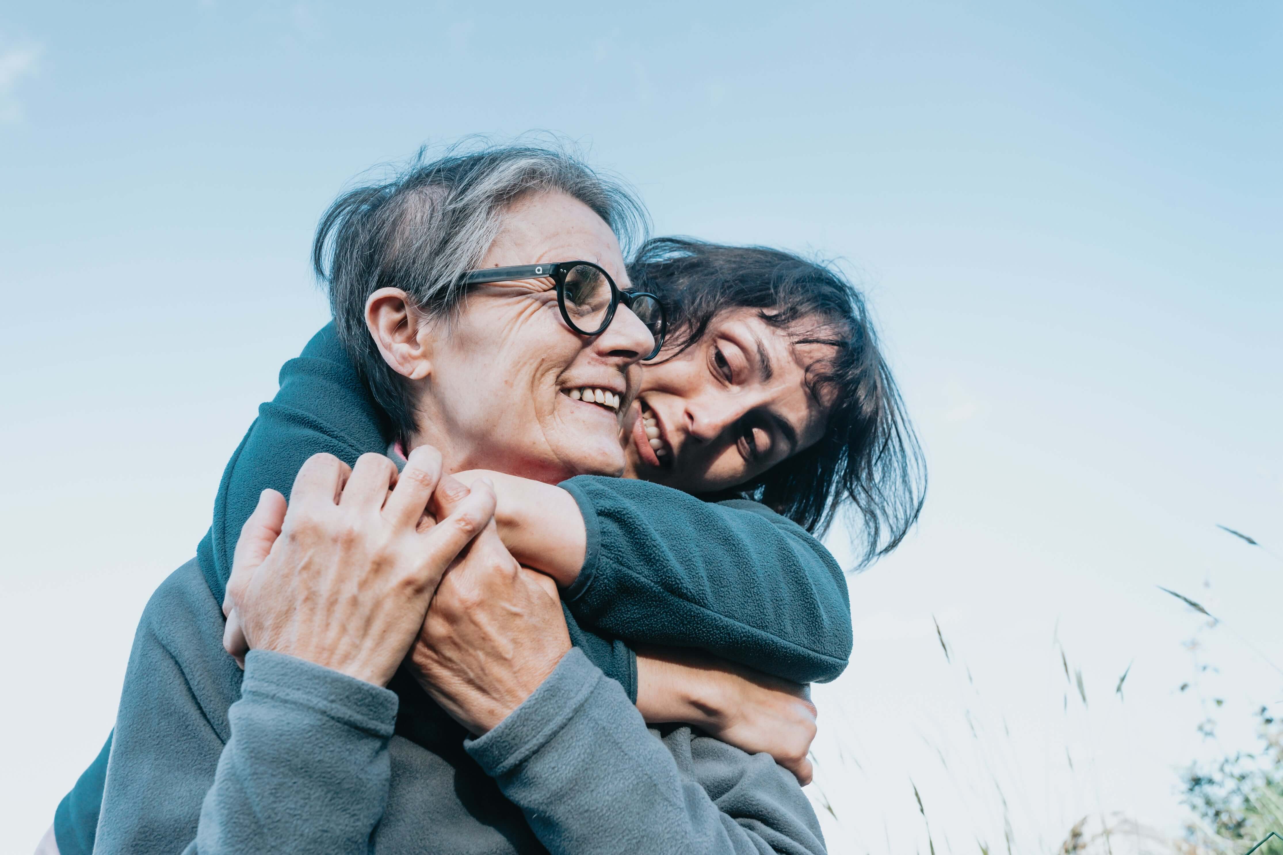 Two people embracing outdoors with a clear sky background
